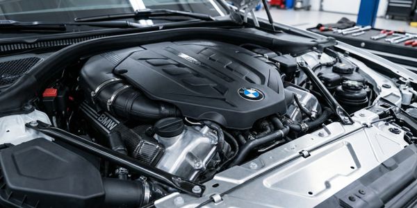 Close-up of a BMW engine under the car hood in a workshop.