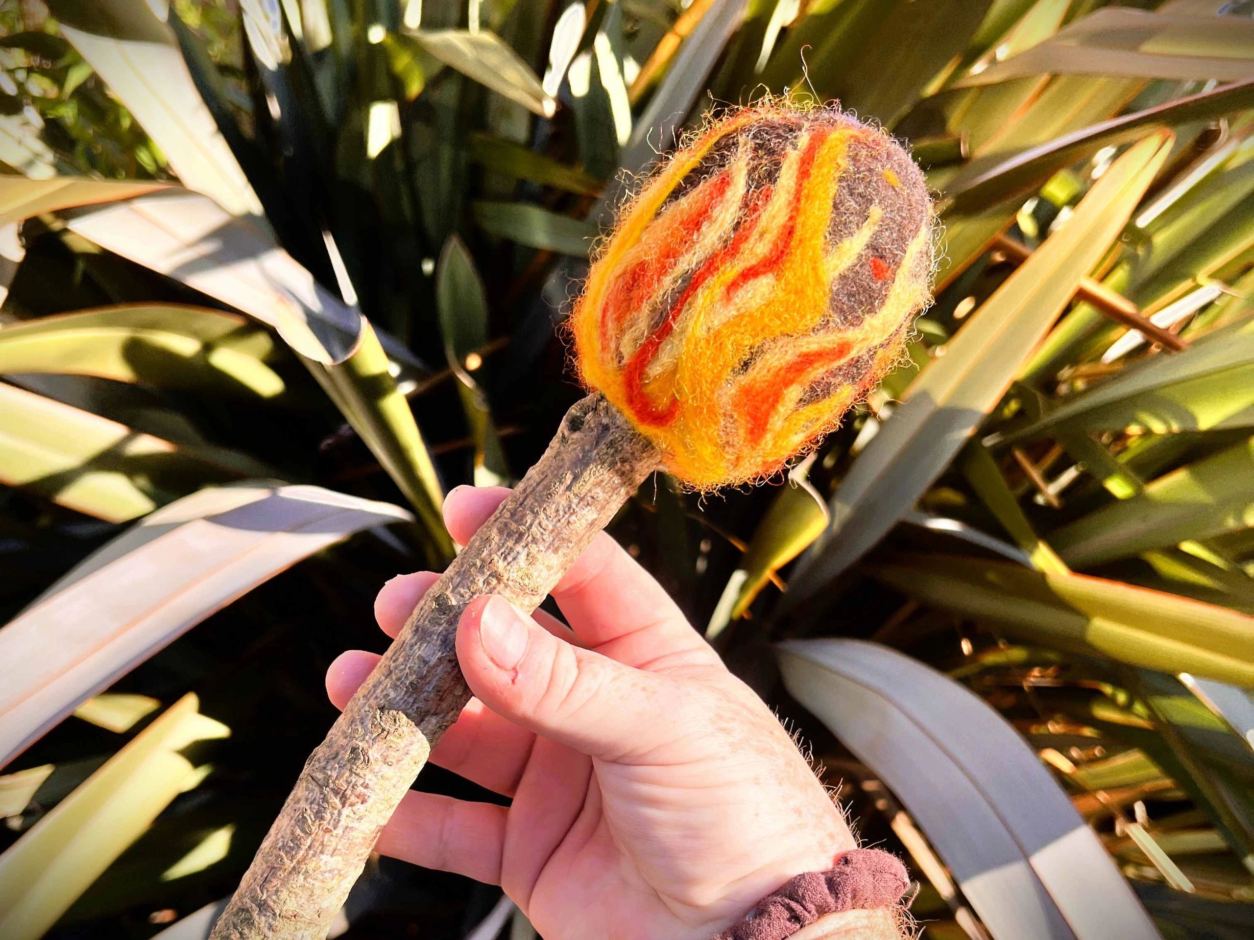 Camp Fire Beater - A black wool base with red, orange and yellow flames coming from the base.
