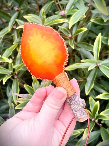 Flame coloured leaf rattle in hand.