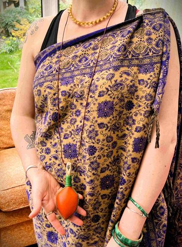 Ruth wearing an orange leaf neck rattle with full length leather cord.