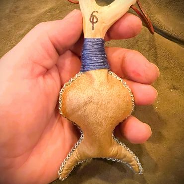 The front of the Horned God Neck Rattle showing shape, stitching, wrap and Oak peg with sigil