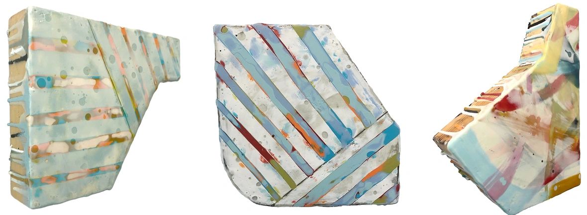 Three ceramic sculptures with colorful striped patterns and angled shapes.