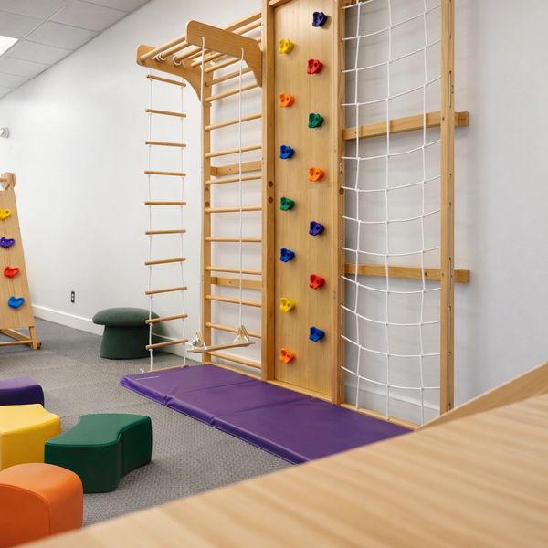 Indoor climbing and play area with colorful holds and mats.