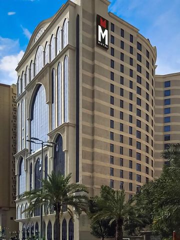M Hotel'in modern binası ve palmiyeler.
