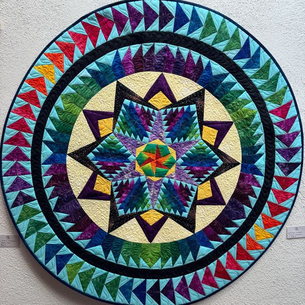 Colorful circular quilt with star and triangle patterns.