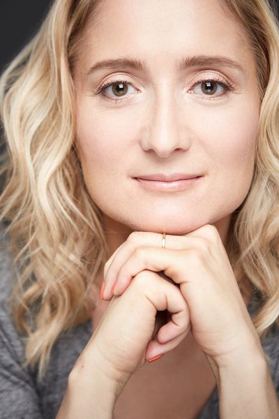 Close-up of a thoughtful woman with blonde hair resting her chin on her hands.