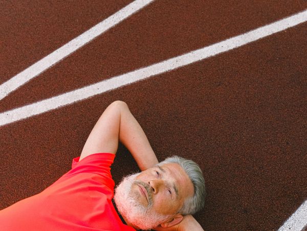 White man lying on a race track with arms folded behind his head.