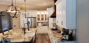 White kitchen remodel with custom range hood, quartz counters, and wood floors