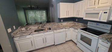 L-shaped white kitchen with granite countertops and efficient layout