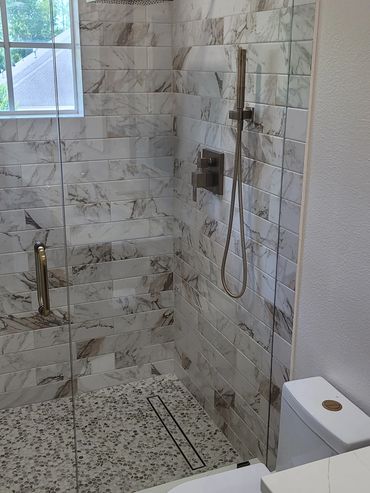 Walk-in shower with marble-look tile and black shower hardware