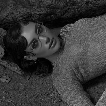 woman lying down on the beach looking at the camera wearing a pair of Dita  glasses