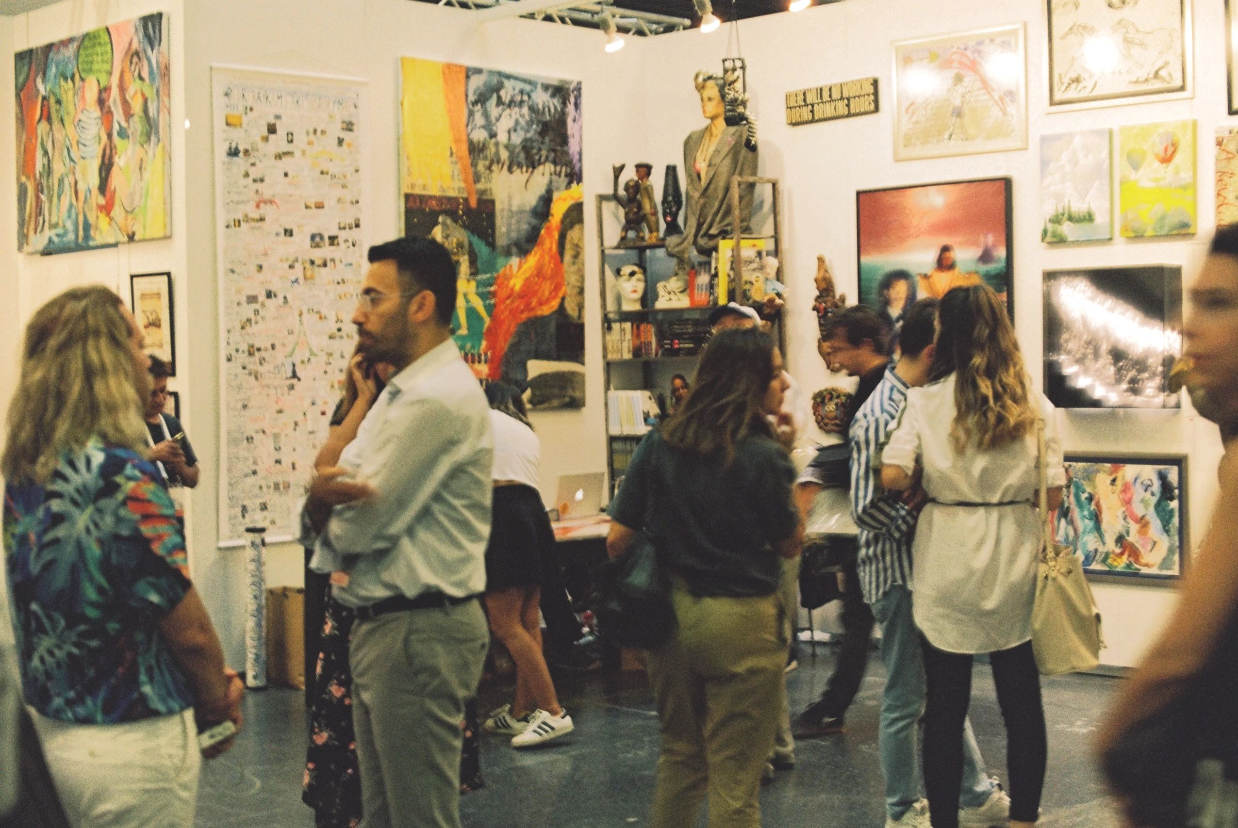 People socializing at an art gallery with diverse artworks.