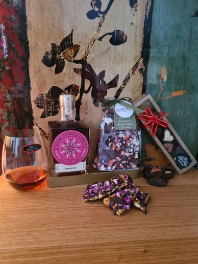 Gin, chocolate, and a glass on a wooden surface with artistic background.
