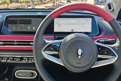 Modern car interior with dual digital displays and a black and red steering wheel.