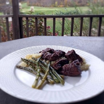 Juicy sirloin tips on a bed of mashed potatoes with a side of roasted asparagus