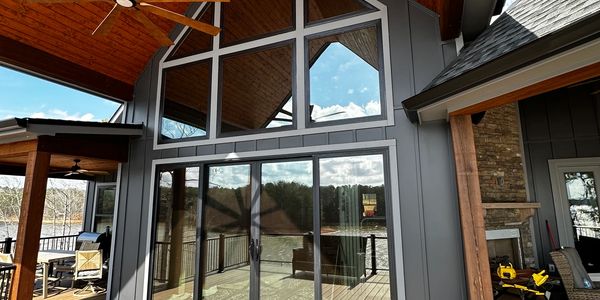 Modern house exterior with large glass windows and wooden ceiling.