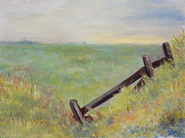 A rustic wooden fence in a lush green field under a soft sky.
