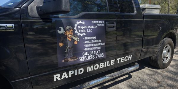 Black service truck with Rapid Mobile Tech advertisement and contact info on door.