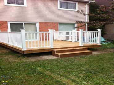 Wooden backyard deck with white railings and steps.