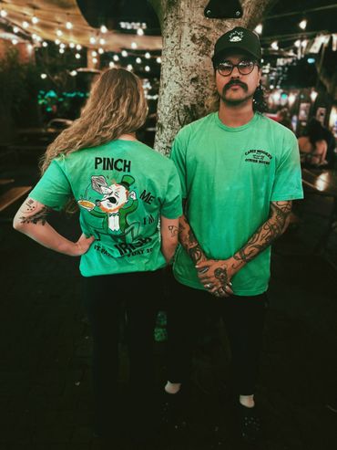 Two people wearing green St. Patrick's Day themed T-shirts at night.