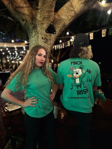 Two people in green shirts celebrating St. Patrick's Day at night.