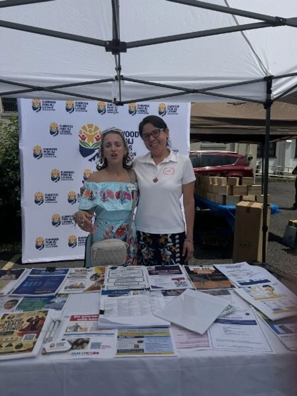 Two women at an informational booth under a tent.