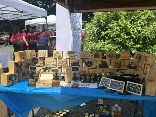 Outdoor market stall selling wooden art and tea.