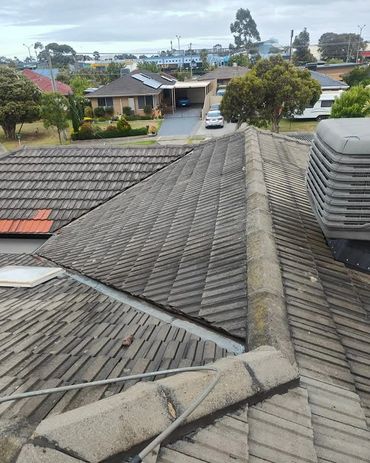 View of rooftops with grey tiles on a cloudy day in a suburban neighborhood.