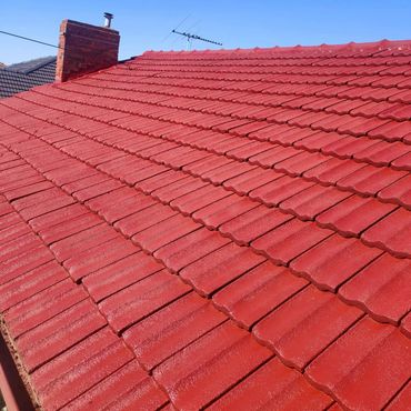 Newly painted red tile roof under clear blue sky.