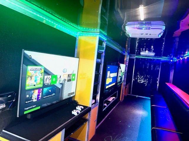 Interior of a gaming trailer with TV screens and LED lights.