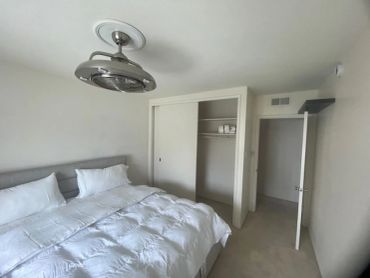 Minimalist bedroom with white bedding and open closet.