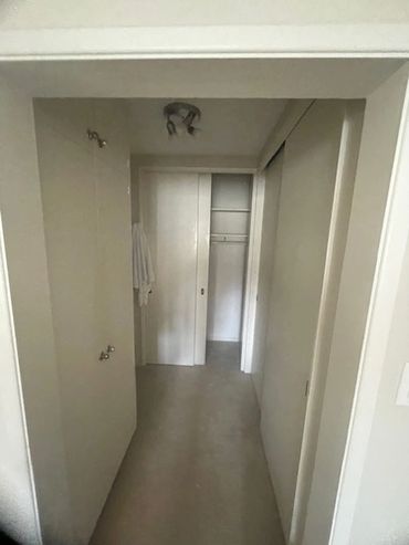 Empty small closet with white sliding doors and a ceiling light fixture.