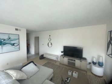 Modern living room with grey sofa, TV, and abstract art on walls.