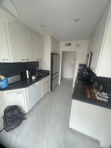 Modern kitchen with white cabinets and black countertops.