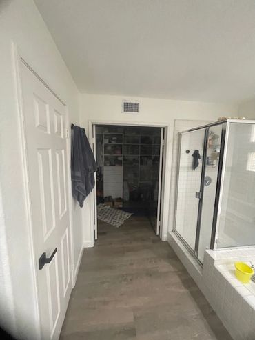 Open doorway leading to a room with shelves and a coat hanging on the door.