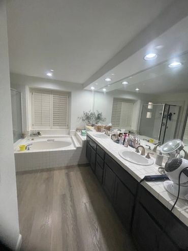 Modern bathroom with dual sinks, bathtub, and bright lighting.