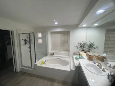 Modern bathroom with a bathtub, shower, and large mirror vanity.