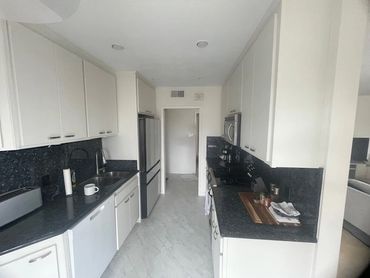 Bright modern kitchen with white cabinets and dark granite countertops.