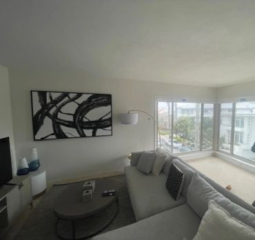 Modern living room with a large gray sofa and abstract wall art.
