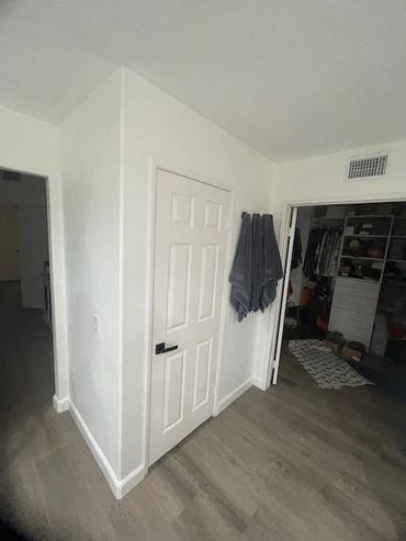 Modern white door with black handle in a minimalistic room with wooden floor.