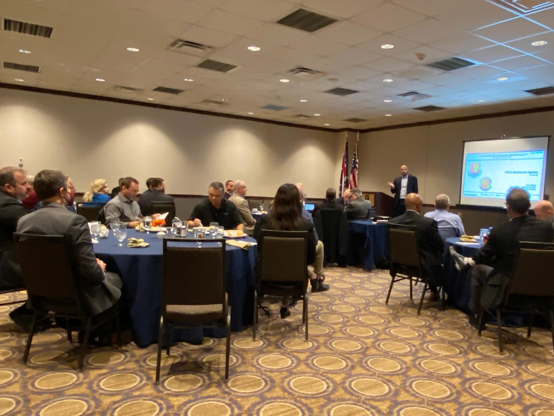 A presenter and an audience sitting at tables