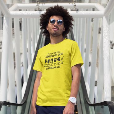 Man wearing a yellow T-shirt with a religious message stands confidently on an escalator.