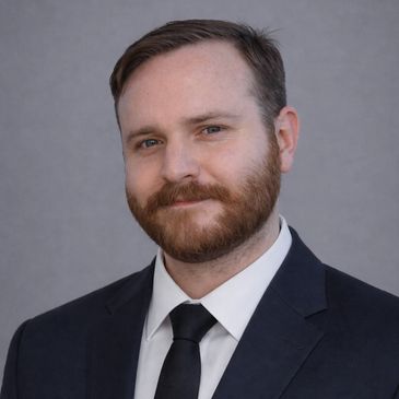 Professional man in a suit and tie smiling gently.