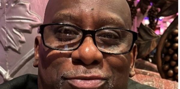 Close-up portrait of a smiling man wearing glasses indoors.