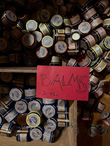 Jars of 2 oz. balms in a wooden box with a red label.