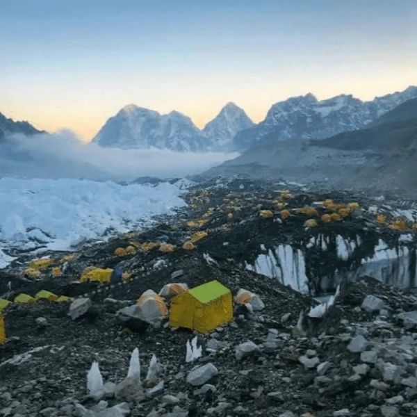 Base camp with tents among snowy mountains.