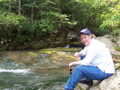 Michele Buckler sitting on a rock by a stream