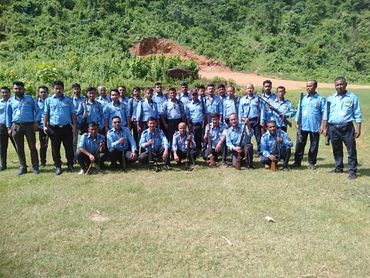 Group of uniformed men holding rifles posing outdoors.