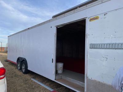 A large white trailer with an open side door on a grassy area.
