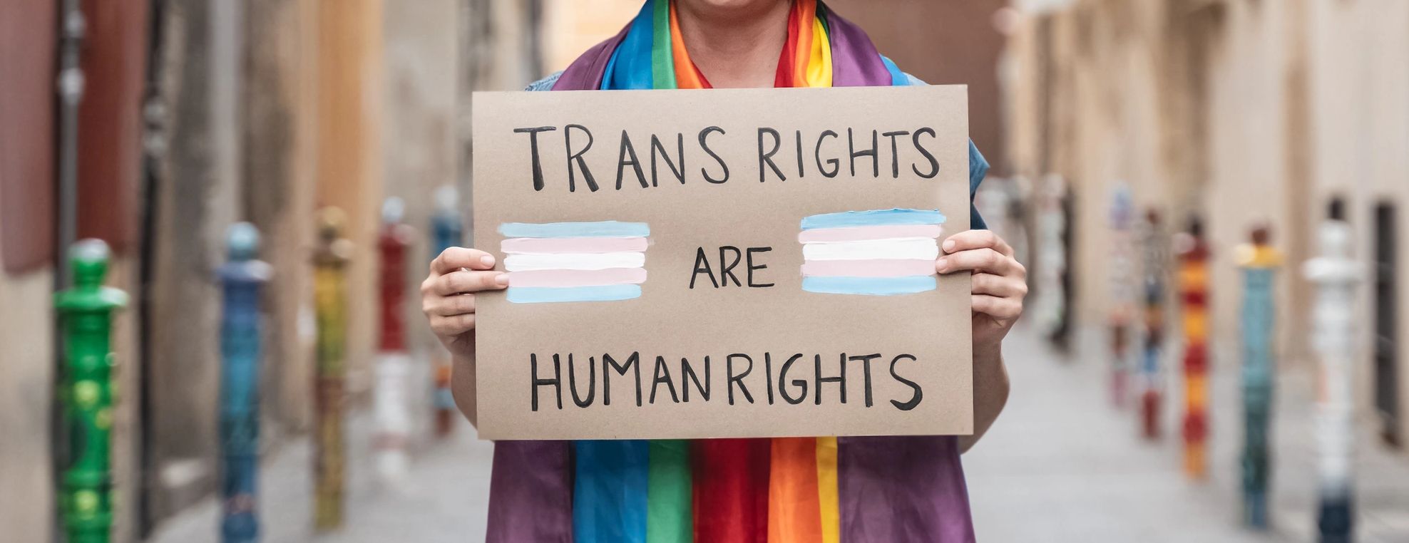 Young person holding a sign that reads "Trans Rights are Human Rights"